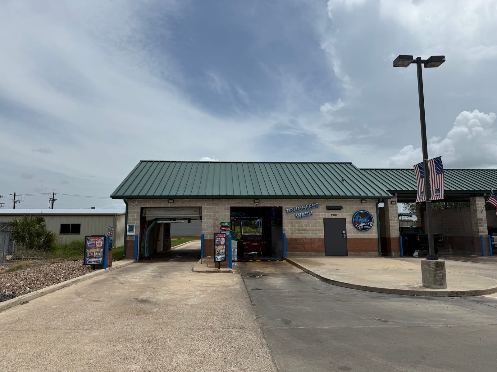 Both touchless automatic wash bays at Gilbert's Car Wash Victoria, with a car mid-wash in one bay.