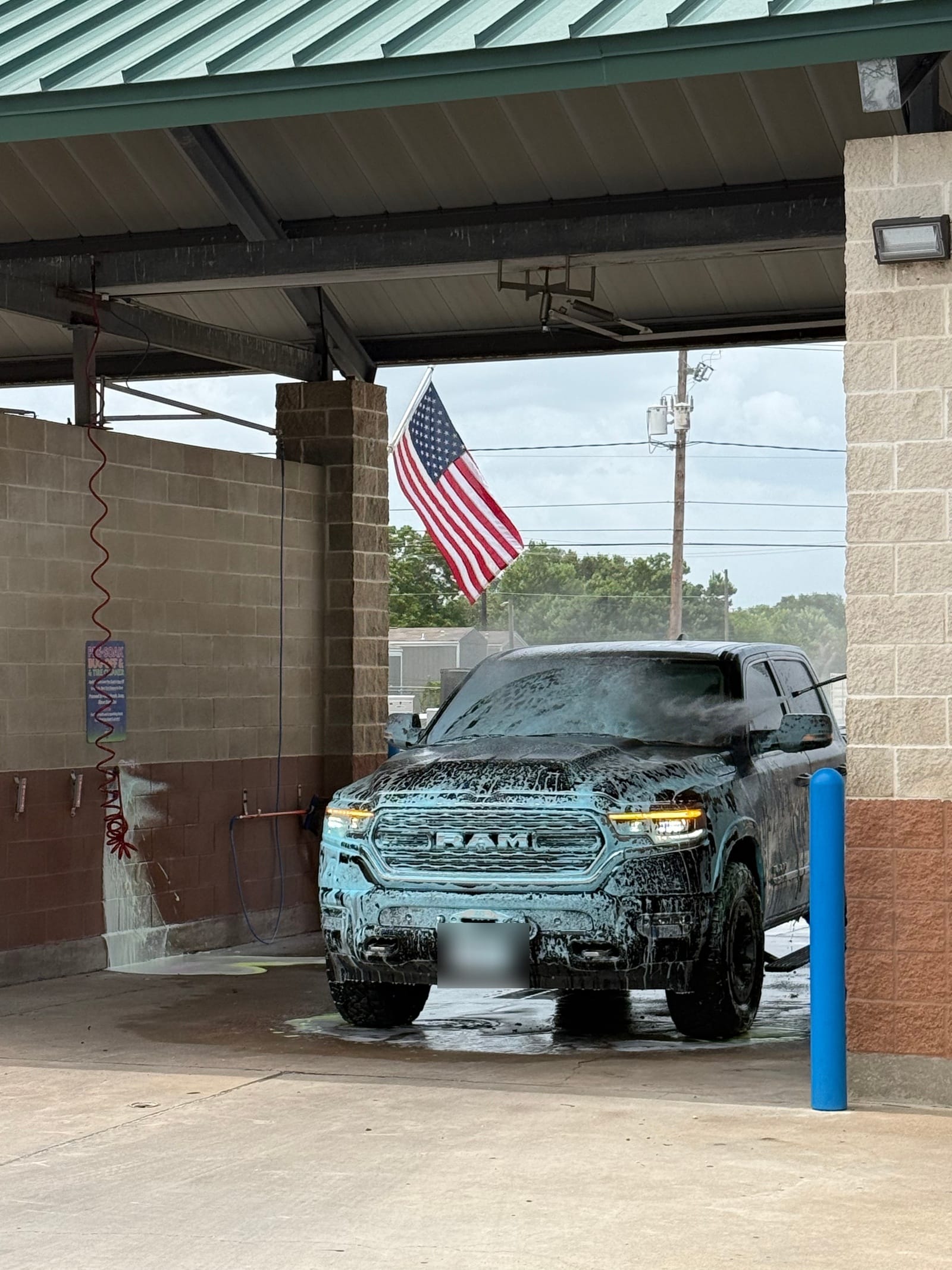 A pickup truck covered in thick foam in a self-serve wash bay at Gilbert's Car Wash Victoria.